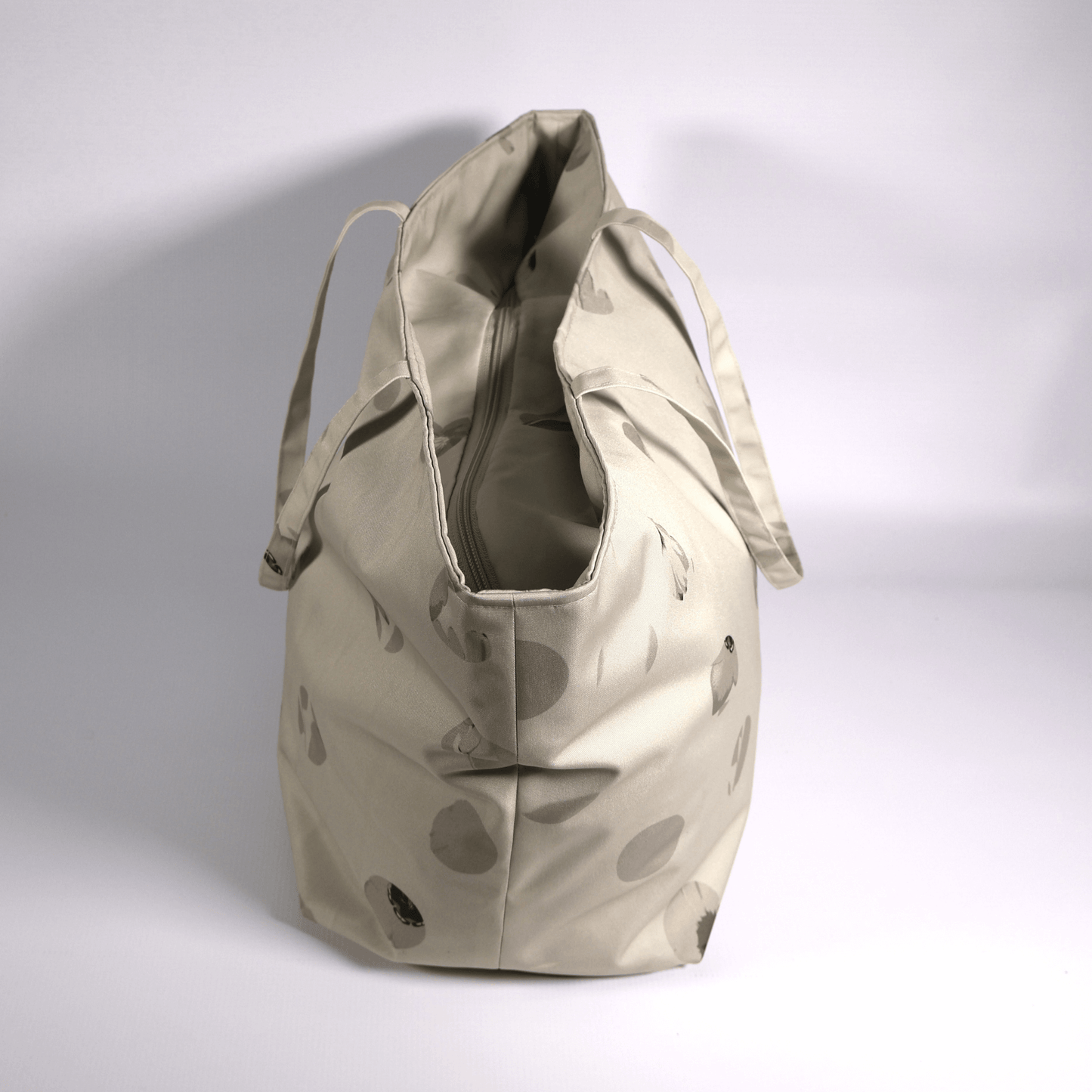 A beige and ivory carryall bag with a abstract floral design. Side view.