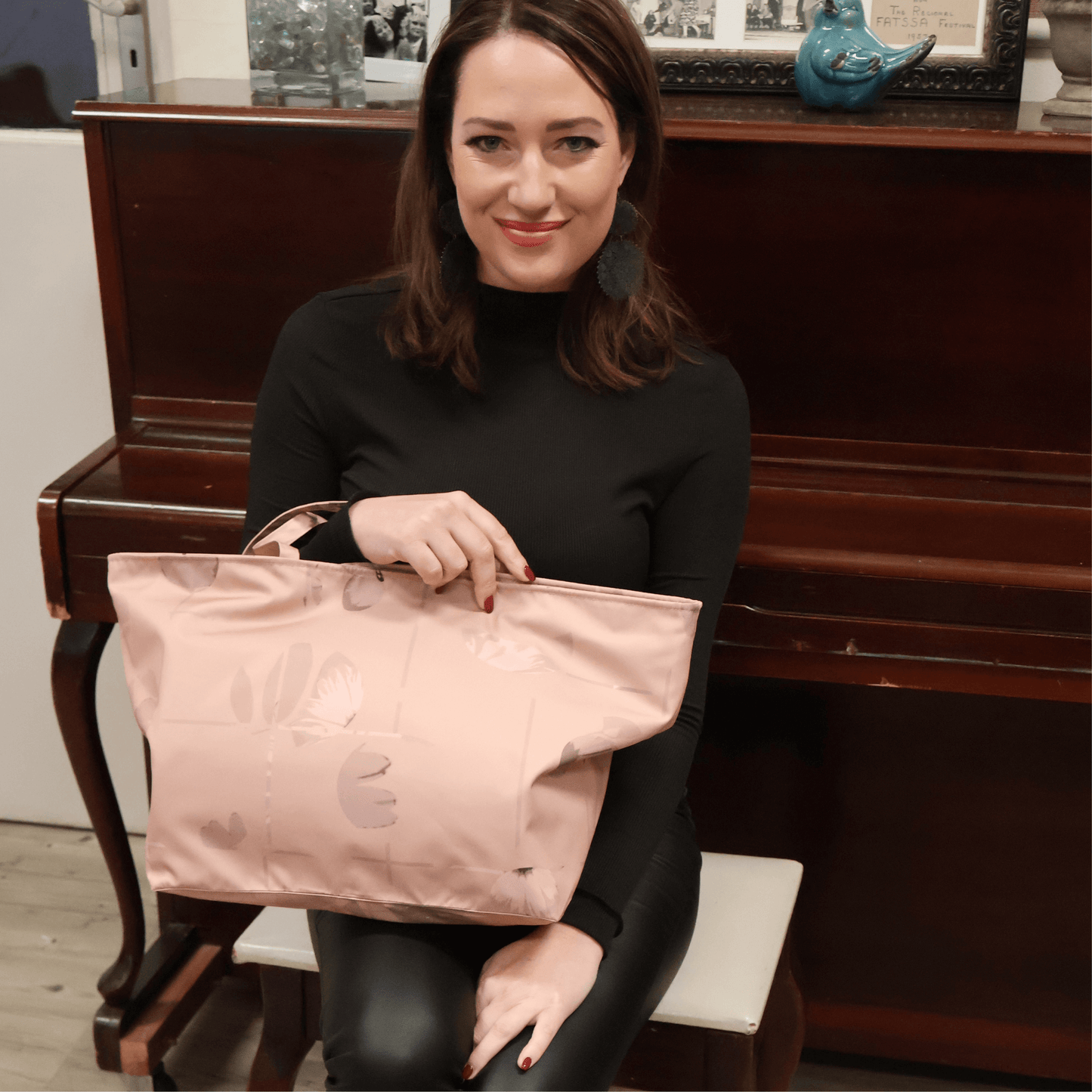 Model with A dusky dark peach carryall bag with a stripe design on her lap.