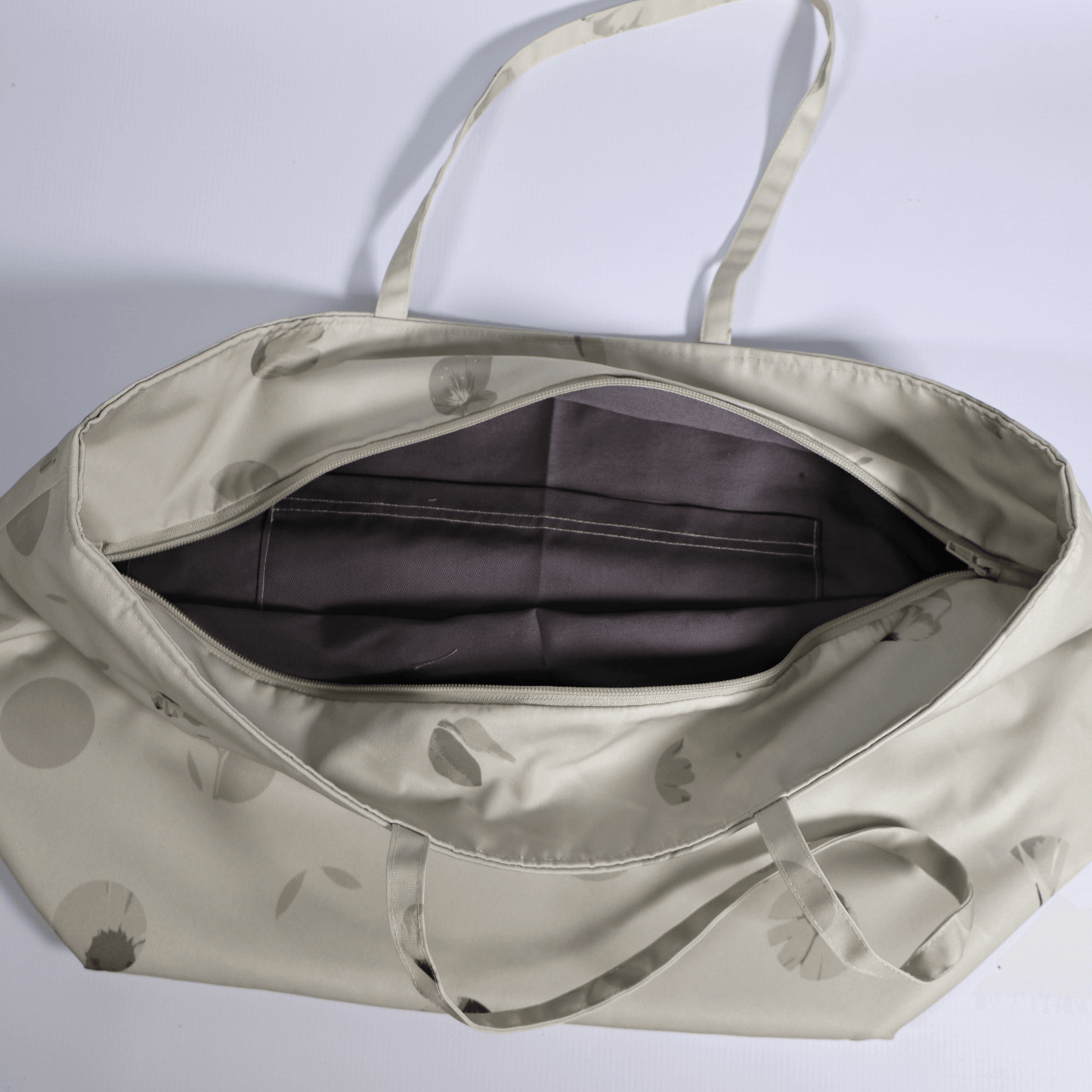 A beige and ivory carryall bag with a abstract floral design. Top view open.