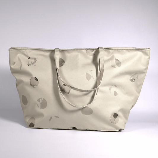 A beige and ivory carryall bag with a abstract floral design.