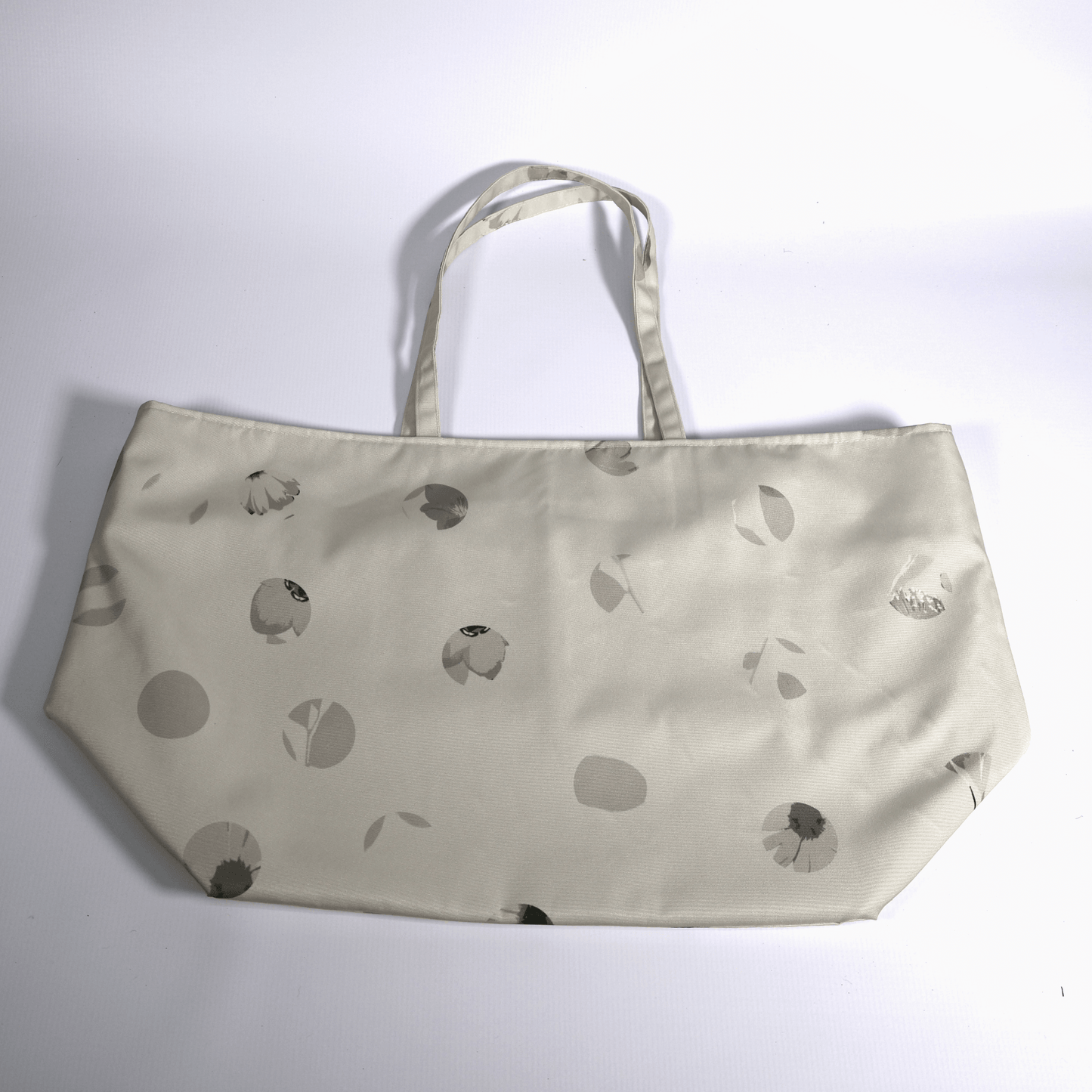 A beige and ivory carryall bag with a abstract floral design. Flat view.