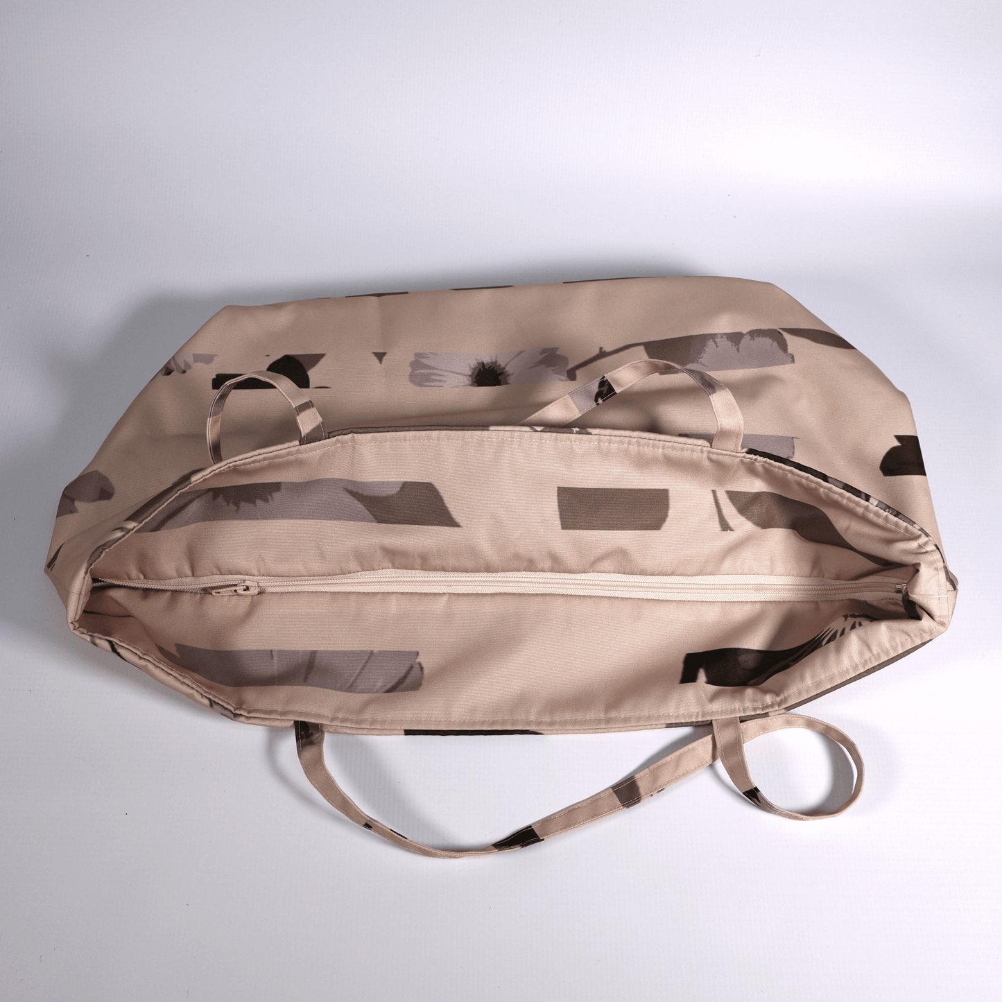 A dusky light peach carryall bag with a stripe design. Top view. Closed zipper.