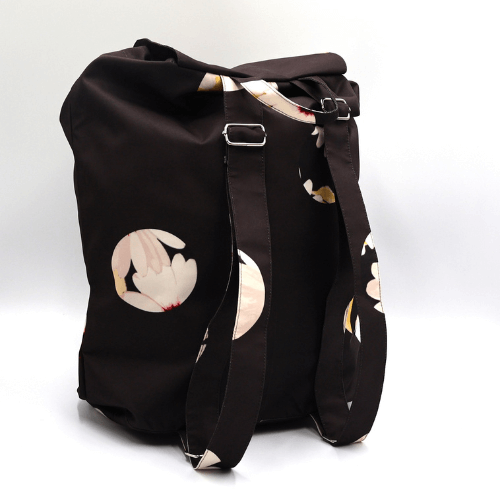 A lightweight, durable backpack with White Daisy design on a black background. High-quality materials. Back view.