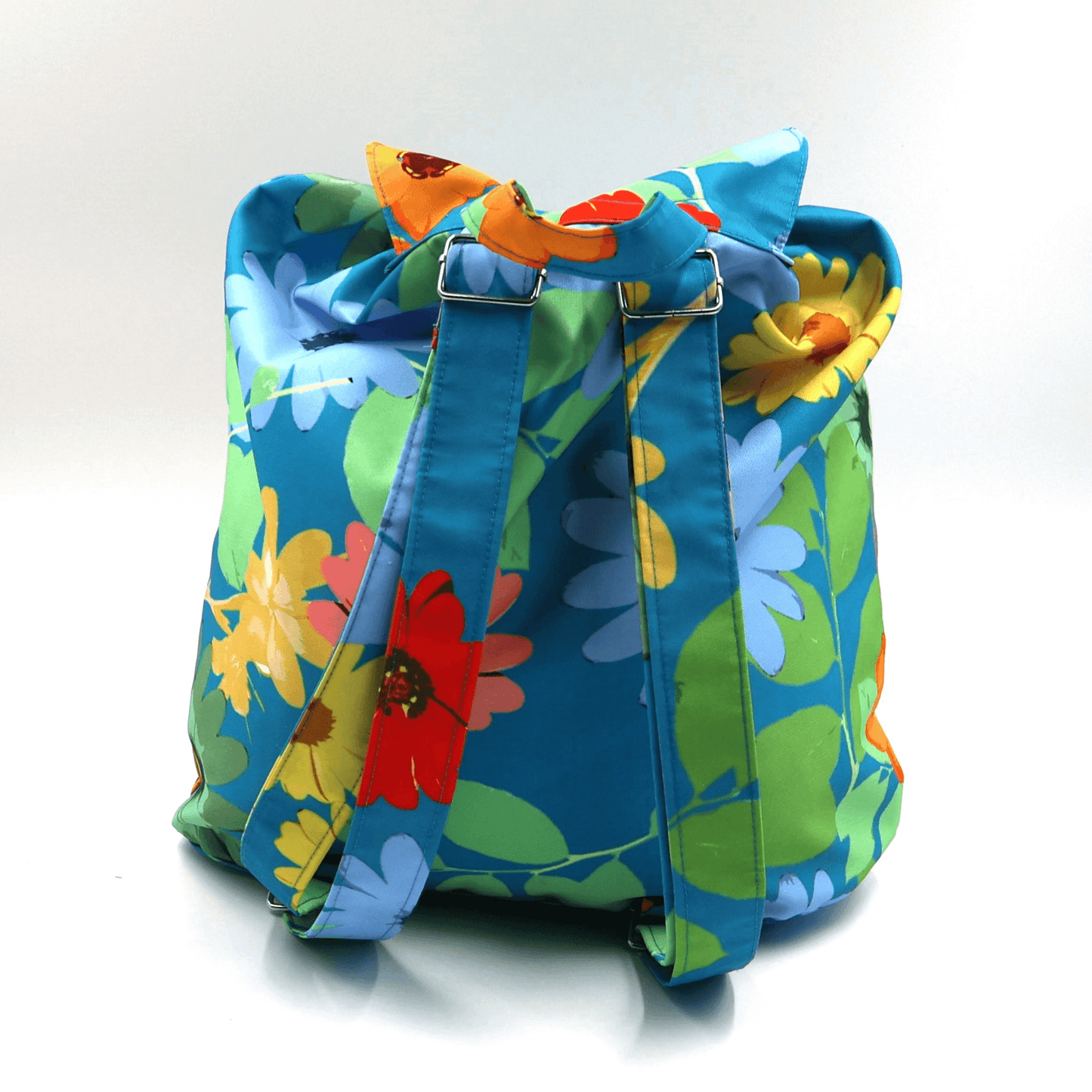 A lightweight, durable backpack with bright, colourful Daisy design on a blue background. View of back with straps.