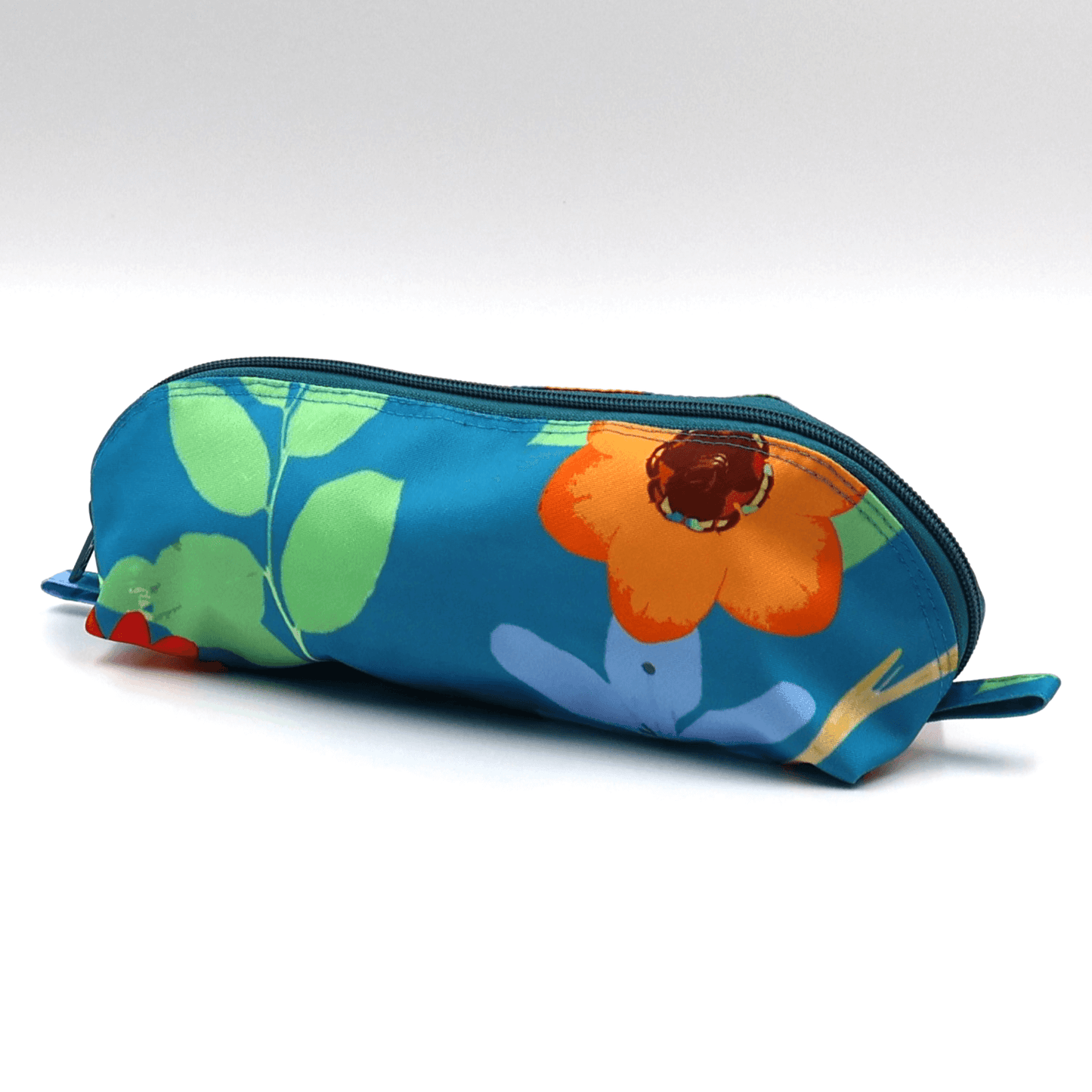 Pencil bag in vibrant daisy floral design on blue background, easy-to-clean fabric and zipper. Side angle.