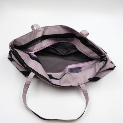 A mauve and dark brown carryall bag with a stripe design. Top view. Open zipper.