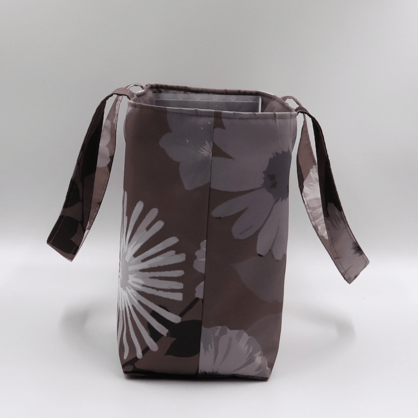 Teacher/book bag with light grey and mauve floral design on a dark mauve background. Carry books and crafts. Side view.