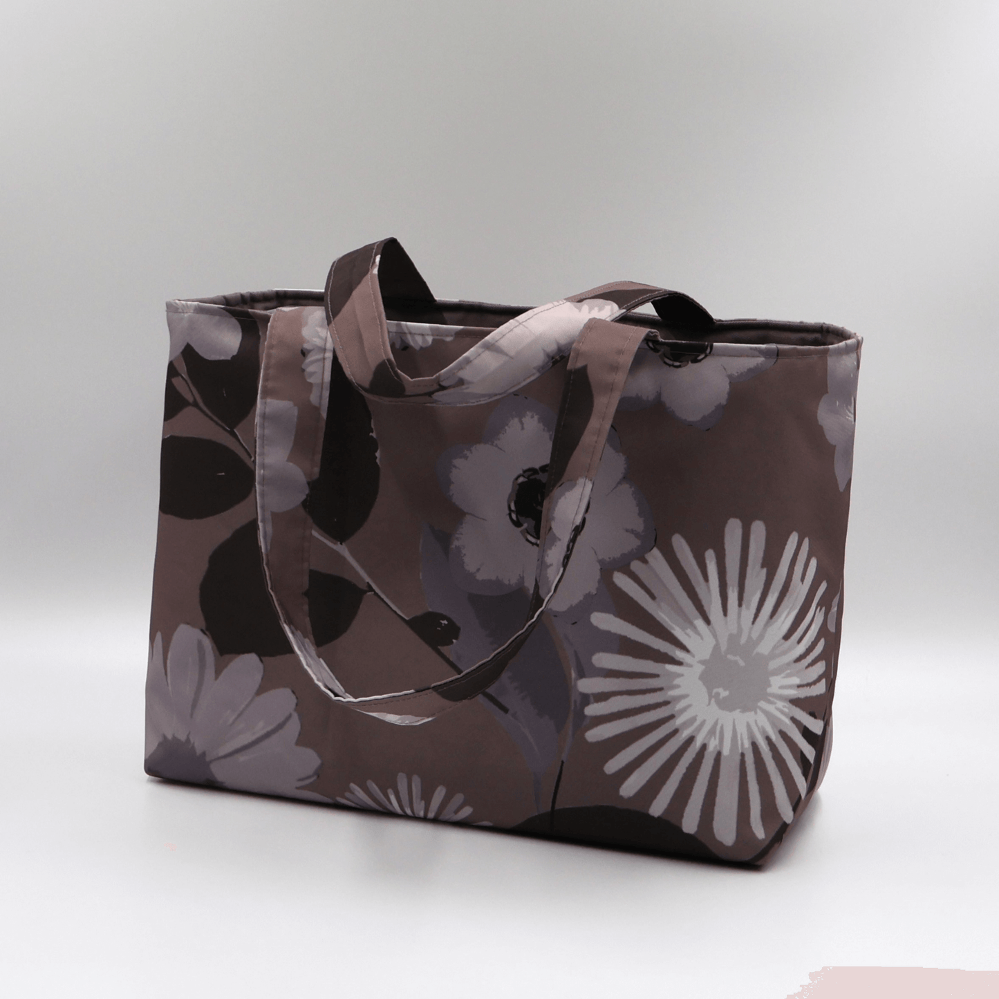 Teacher/book bag with light grey and mauve floral design on a dark mauve background. Carry books and crafts. Side angle.