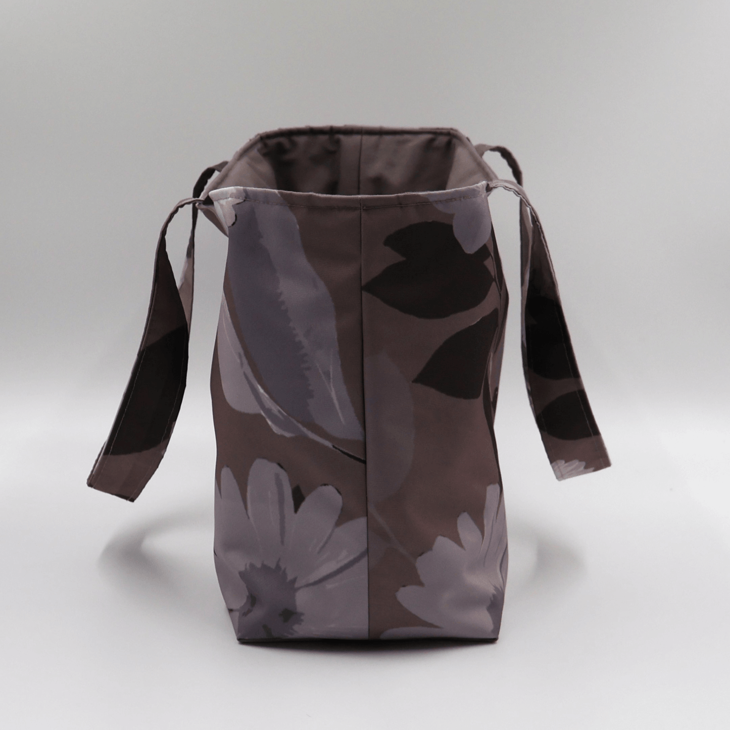 Teacher/book bag with light grey and mauve floral design on a dark mauve background. Carry books and crafts. Side.