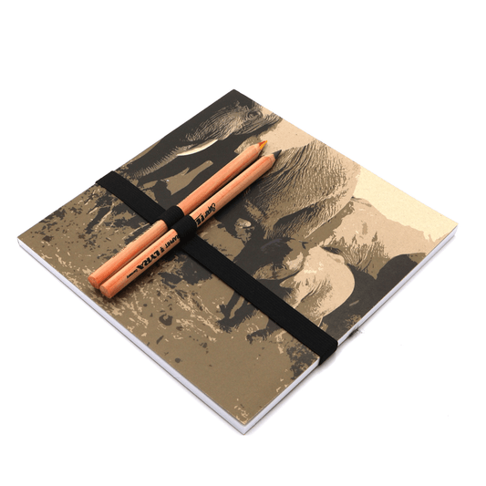 Square art pad with pencils and pencil holder with elephant family design in brown on a beige/sand background.