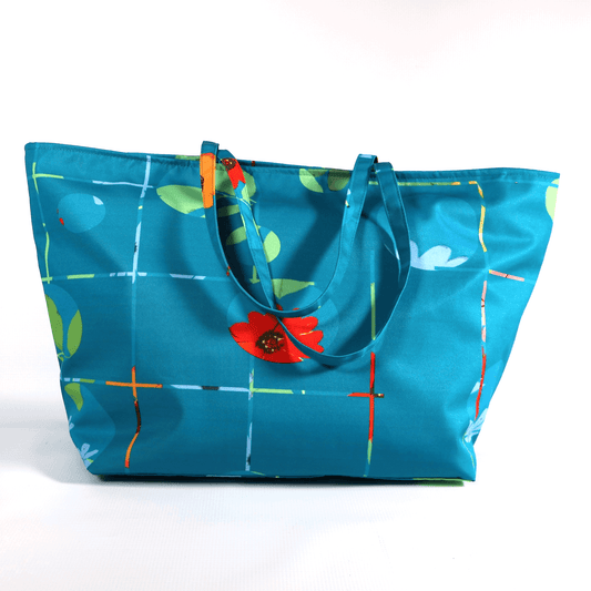 A bright turquoise/blue carryall bag with a multi-colour daisy design.