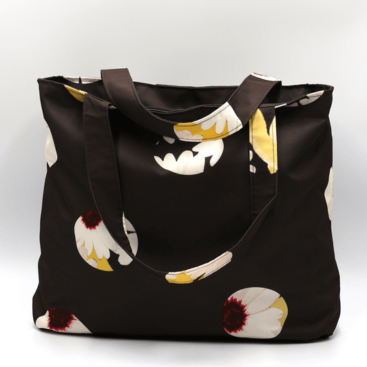 Shoulder bag with white abstract daisy design on a black background. Perfect for carrying books and documents.