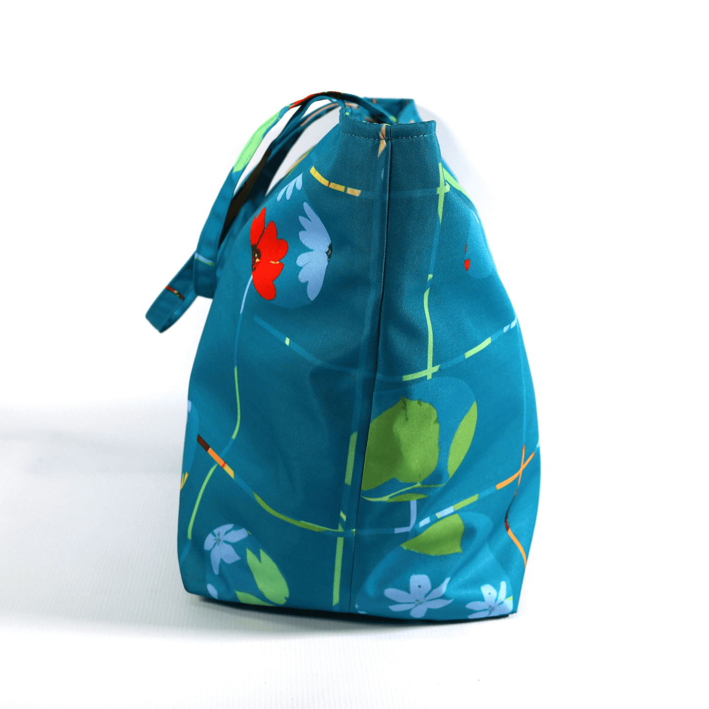 A bright turquoise/blue carryall bag with a multi-colour daisy design. Side view.