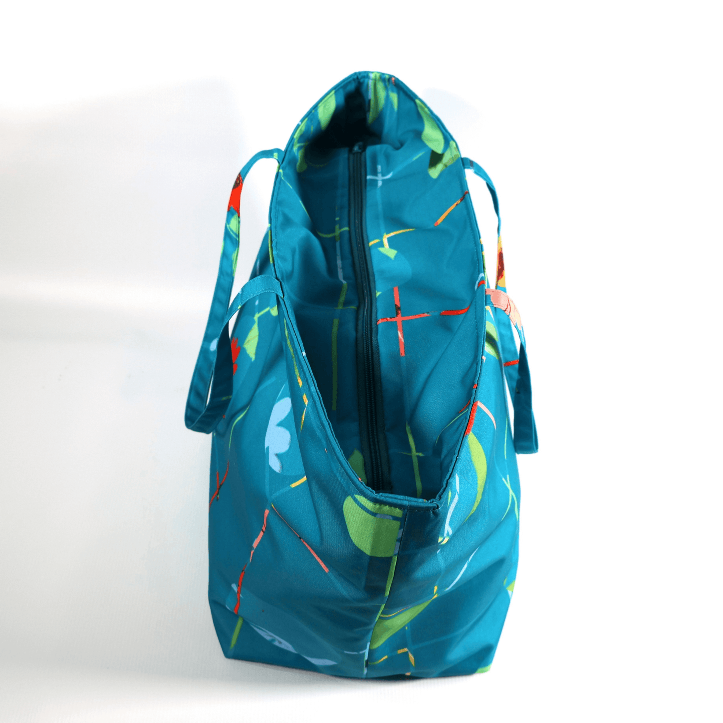 A bright turquoise/blue carryall bag with a multi-colour daisy design. Open zipper.