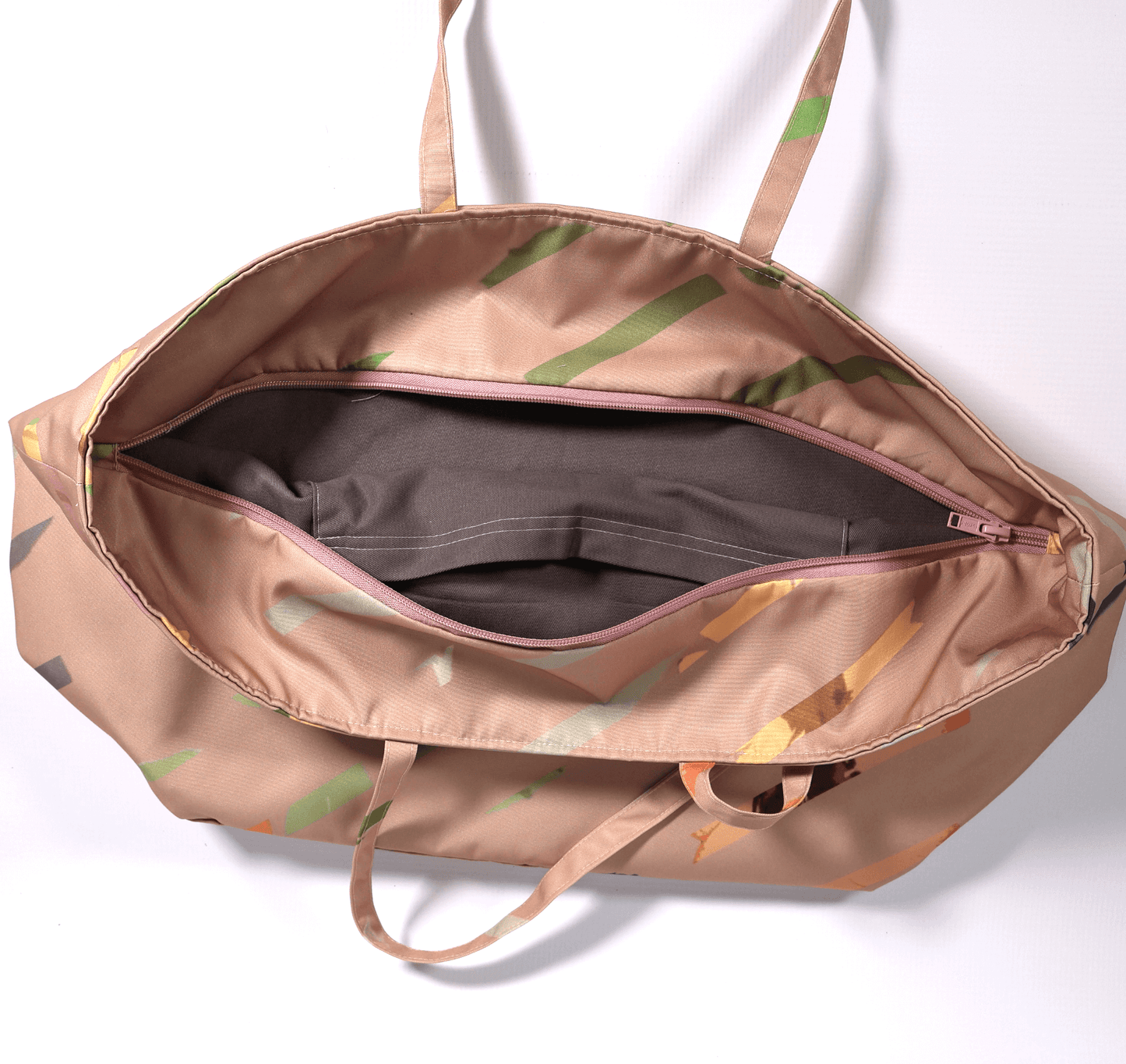 A dusky peach carryall bag with a multi-colour stripe design. Top view. Open zipper.