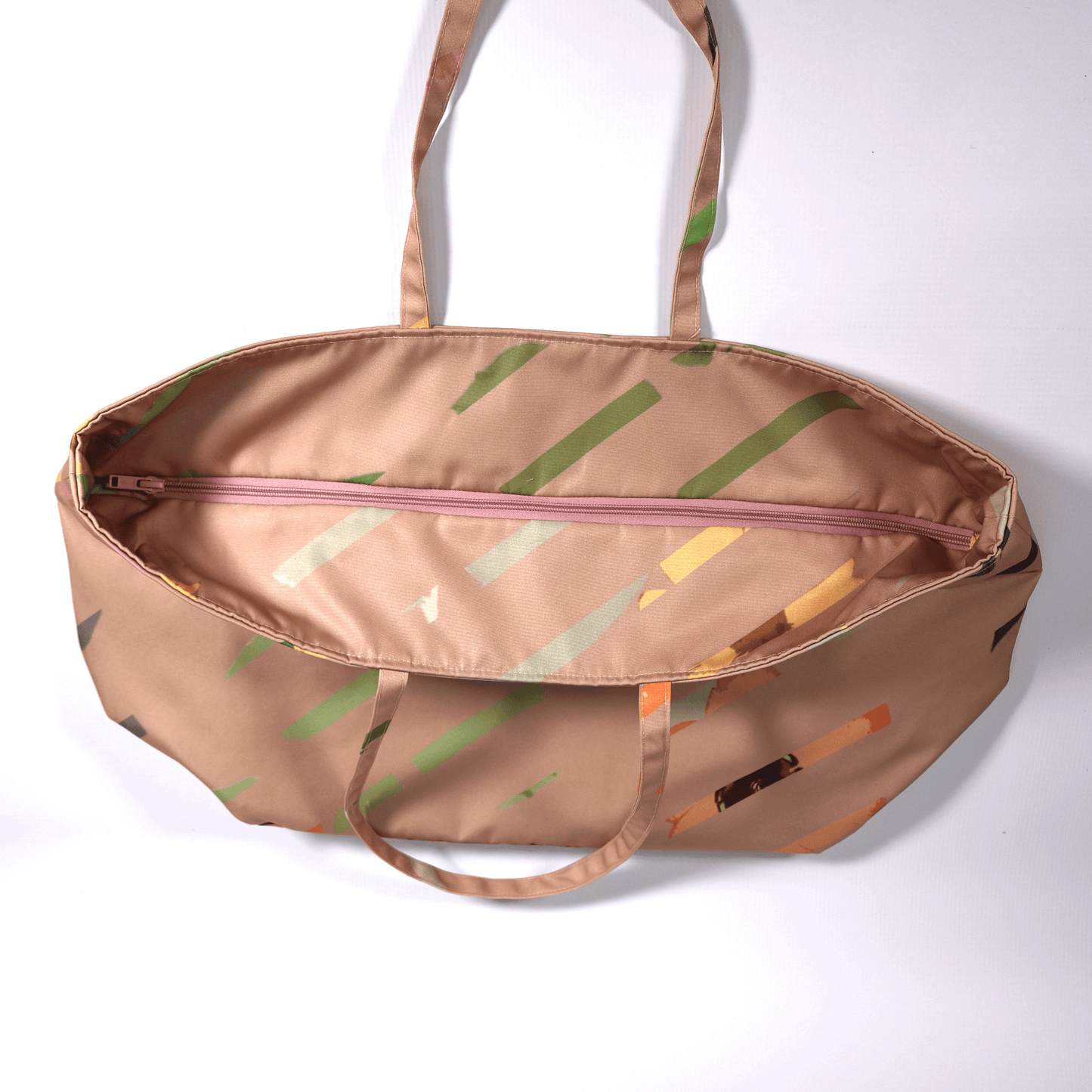 A dusky peach carryall bag with a multi-colour stripe design. Top closed.