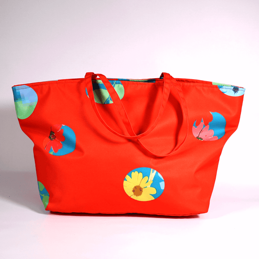 A bright red carryall bag with a stripe abstract floral design.
