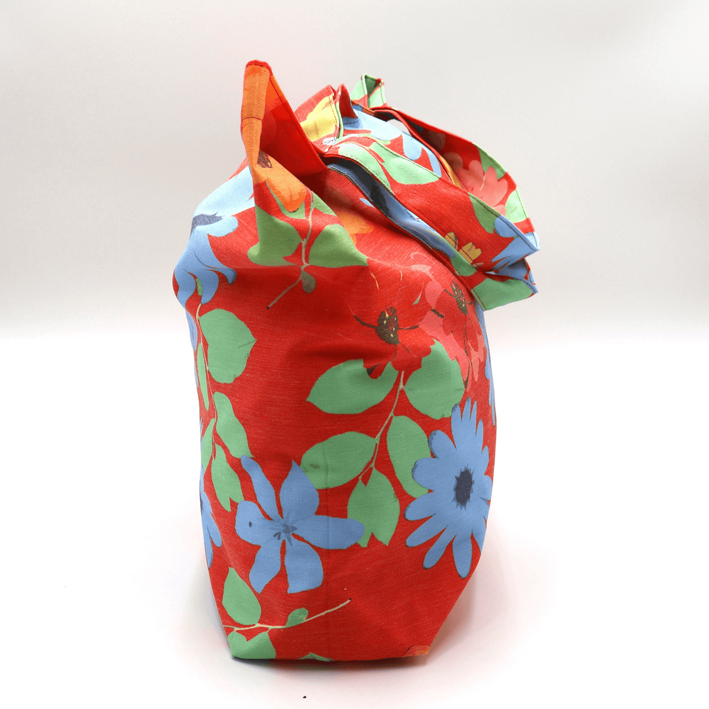 A bright, beautiful tote bag with Daisy design on a red background. Perfect finishes. Side view.
