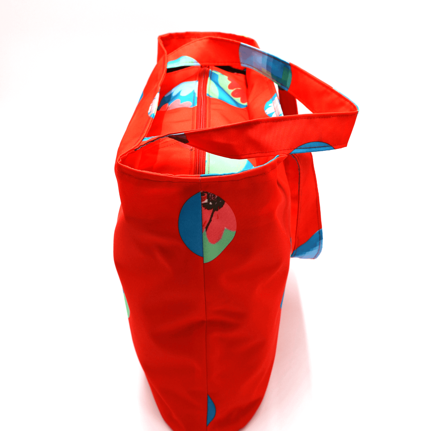 Shoulder bag with bright daisy floral design on a red background. Perfect for carrying books and documents. Top view.