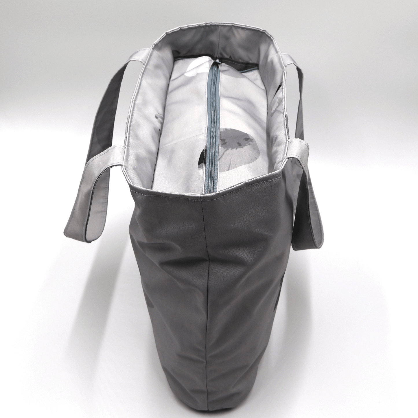 Shoulder bag with daisy floral design in dark and light grey. Zipped closure. Top view.