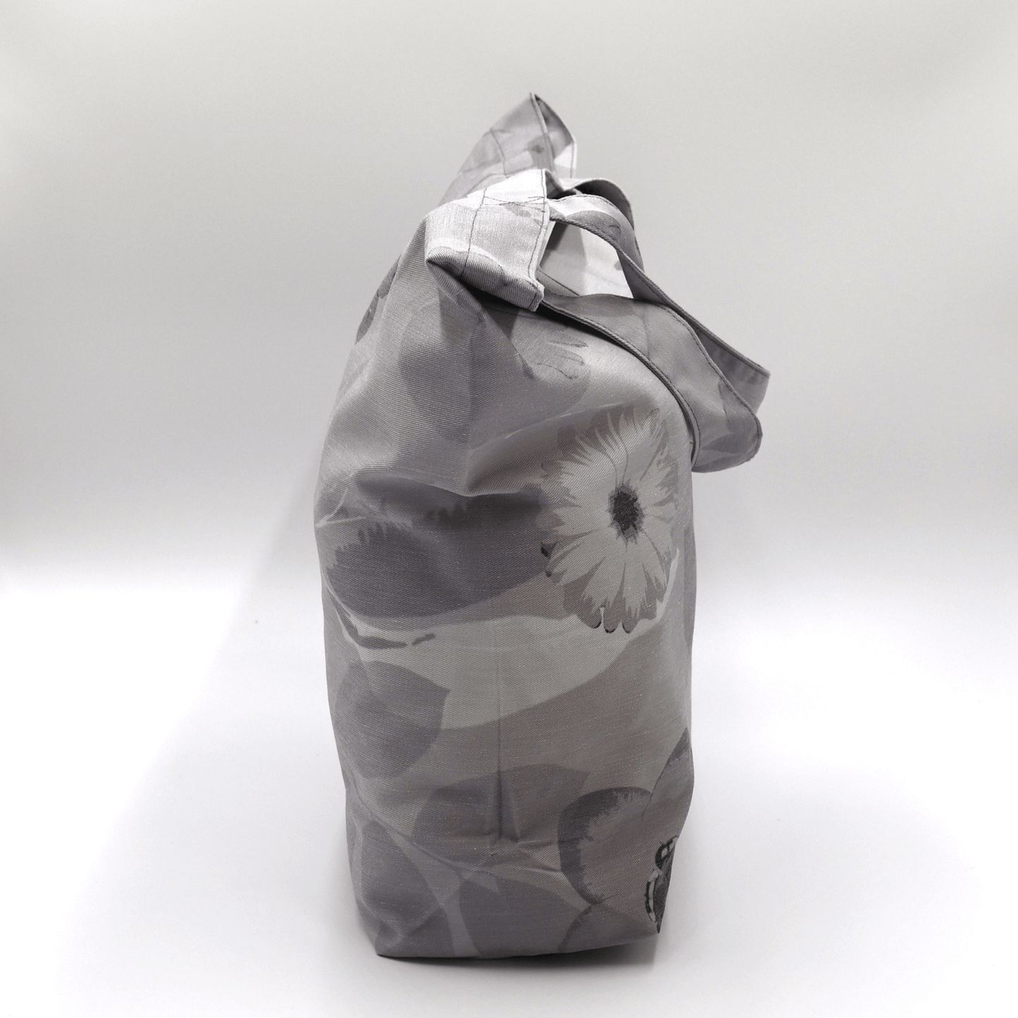 A big, beautiful tote bag with Daisy design in different tones of grey. High-quality material and finishes. Side view.