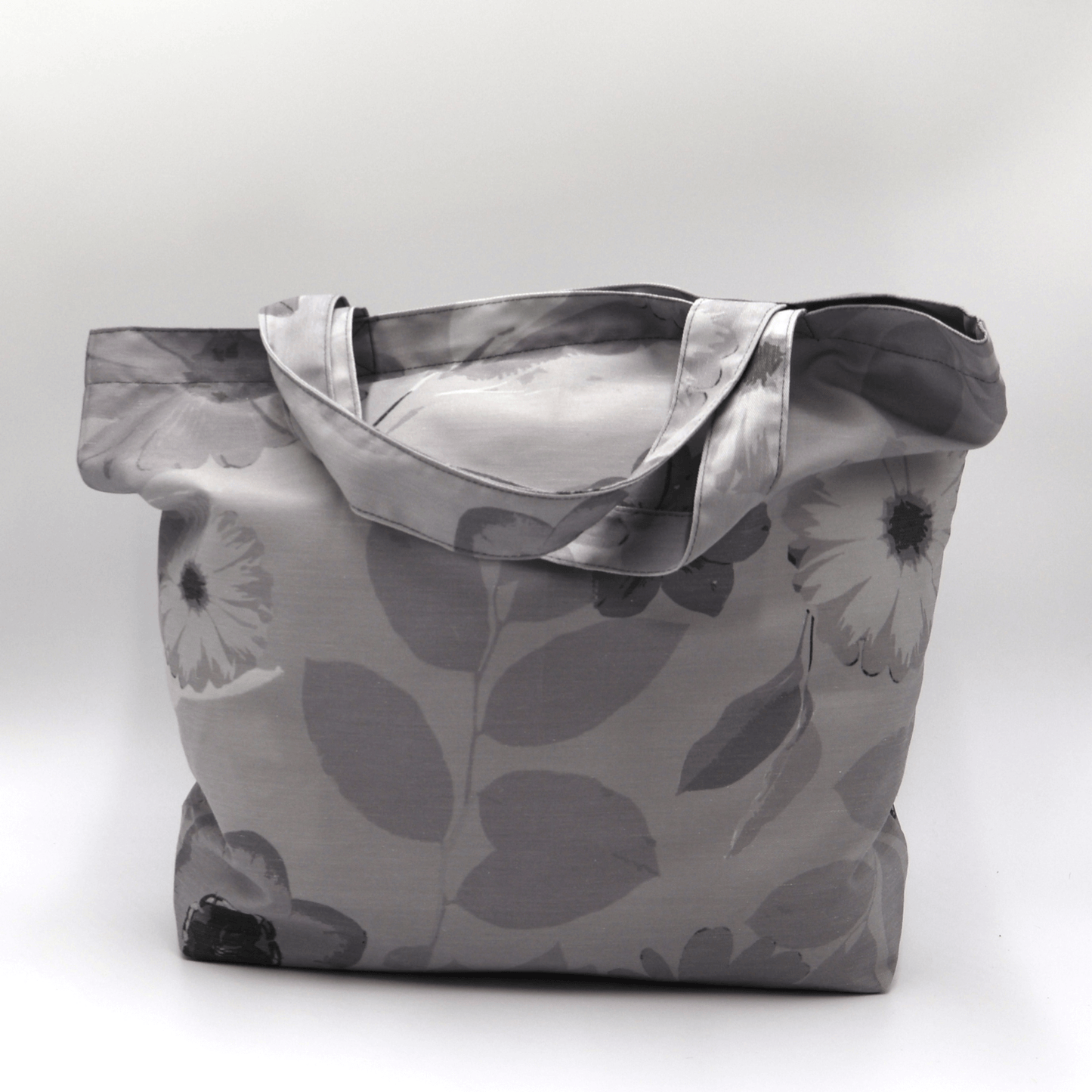 A big, beautiful tote bag with Daisy design in different tones of grey. High-quality material and finishes. Front view.