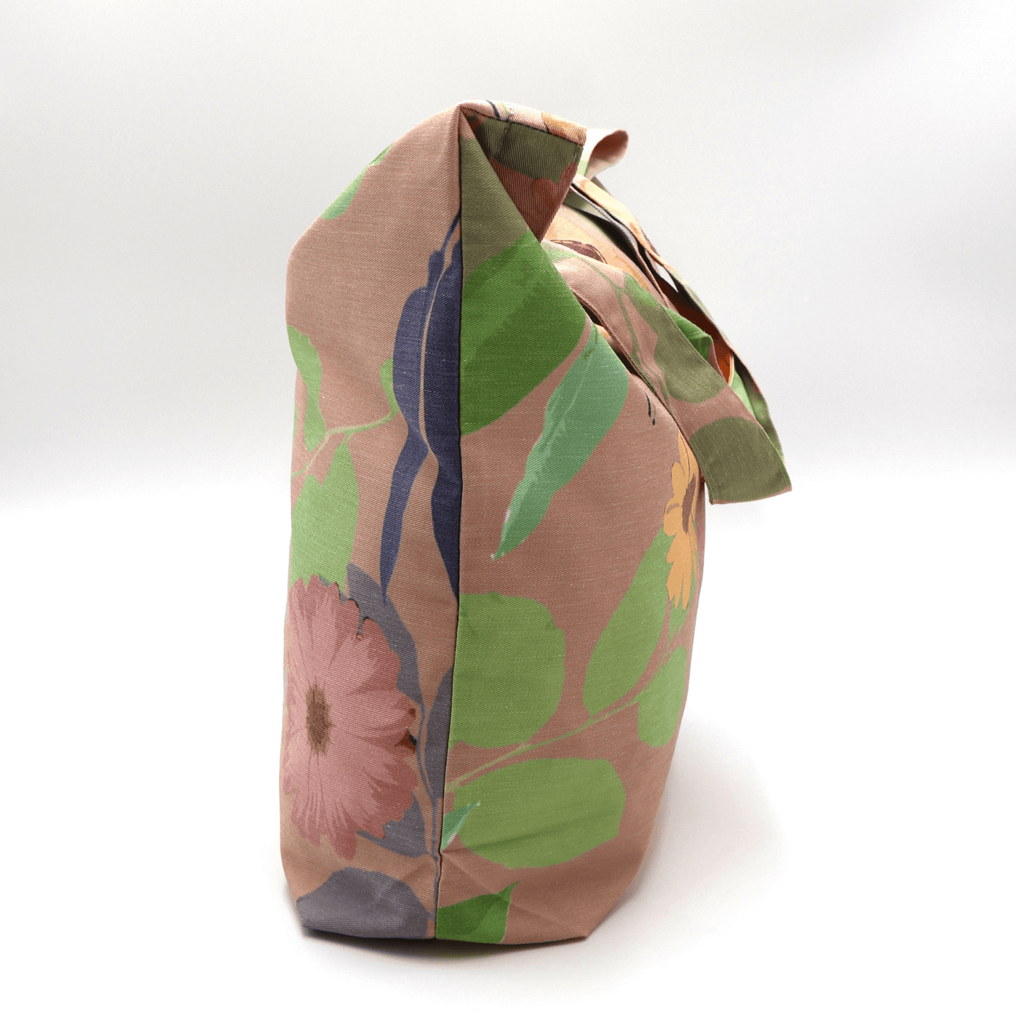 A high-quality tote bag with orange and yellow Daisy floral design on peach background. Side view.