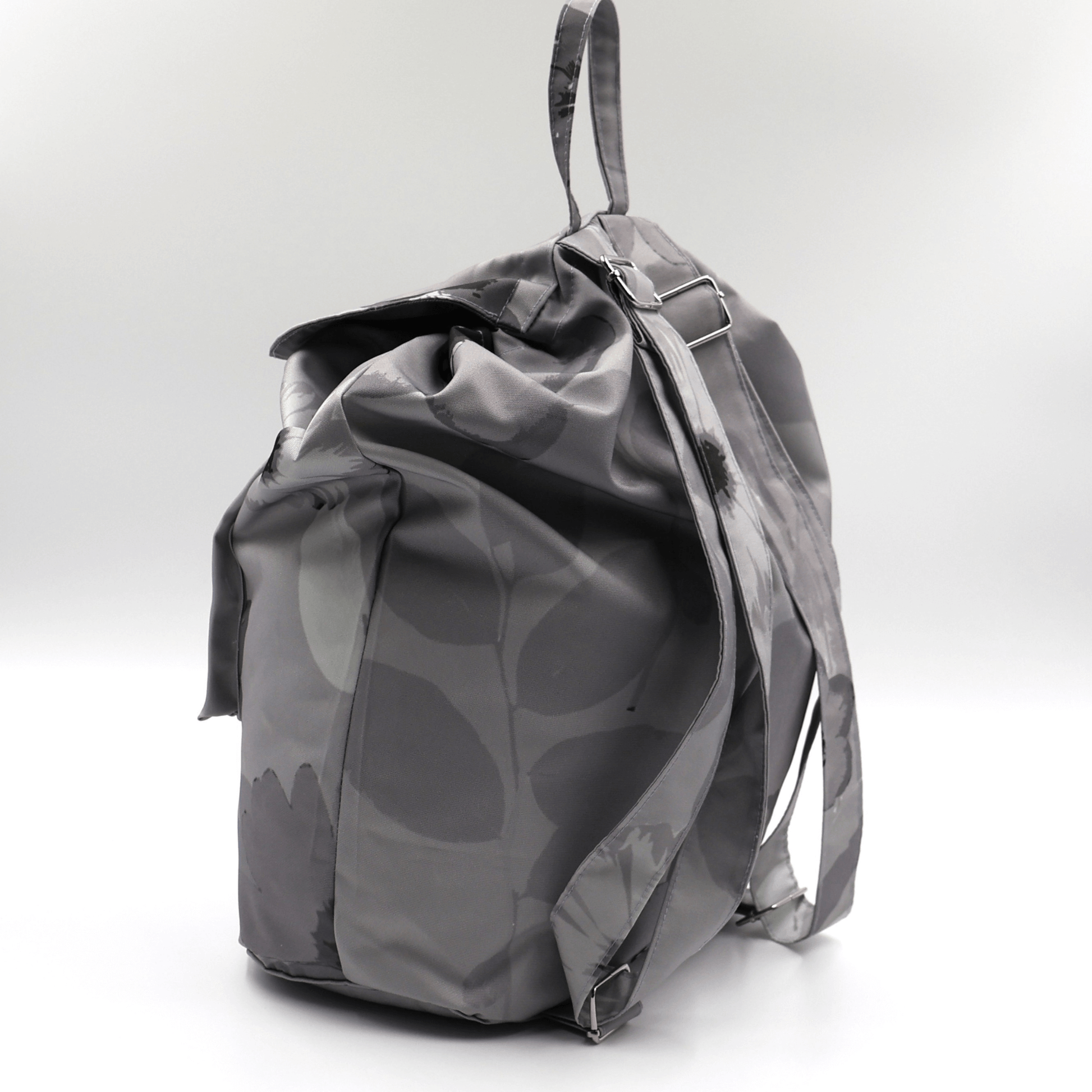 Lightweight backpack with drawstring and daisy floral design in dark and light greys. Side angle.