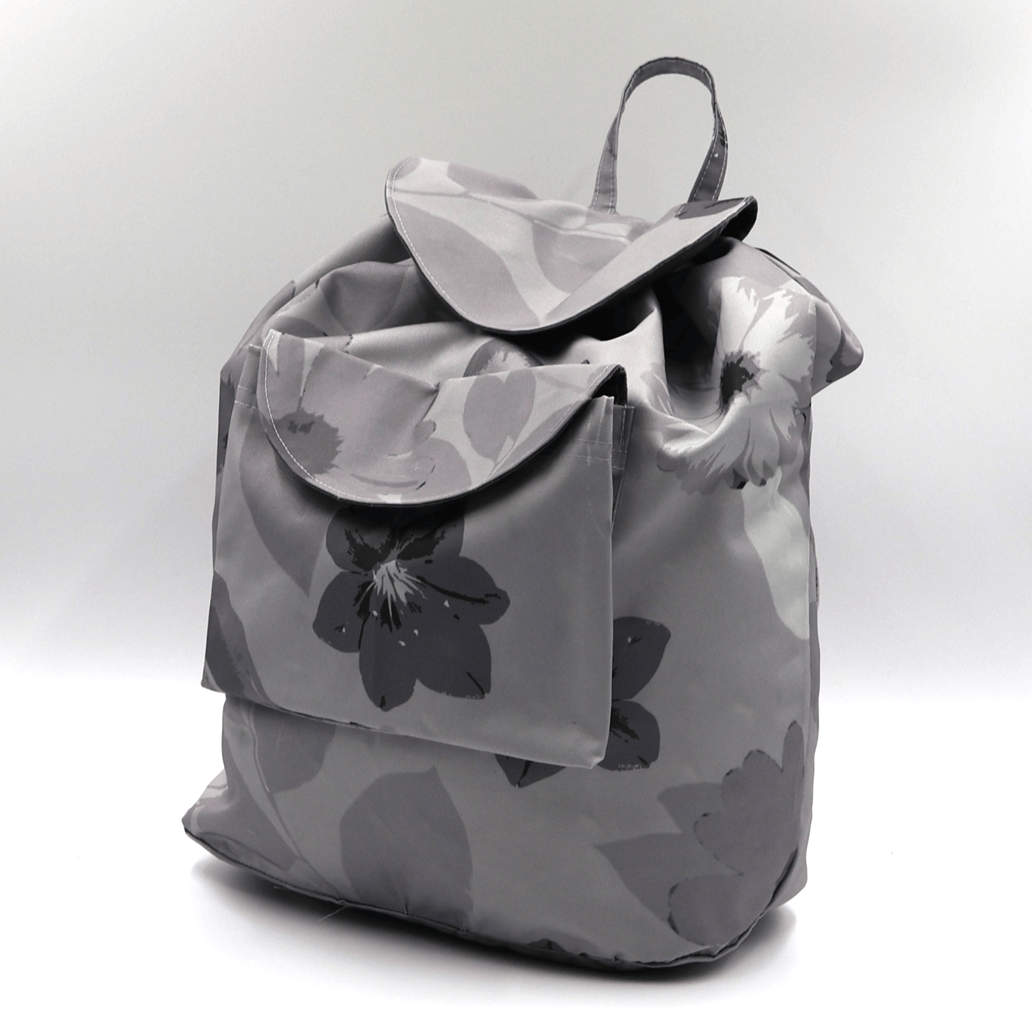 Lightweight backpack with drawstring and daisy floral design in dark and light greys. Side View.