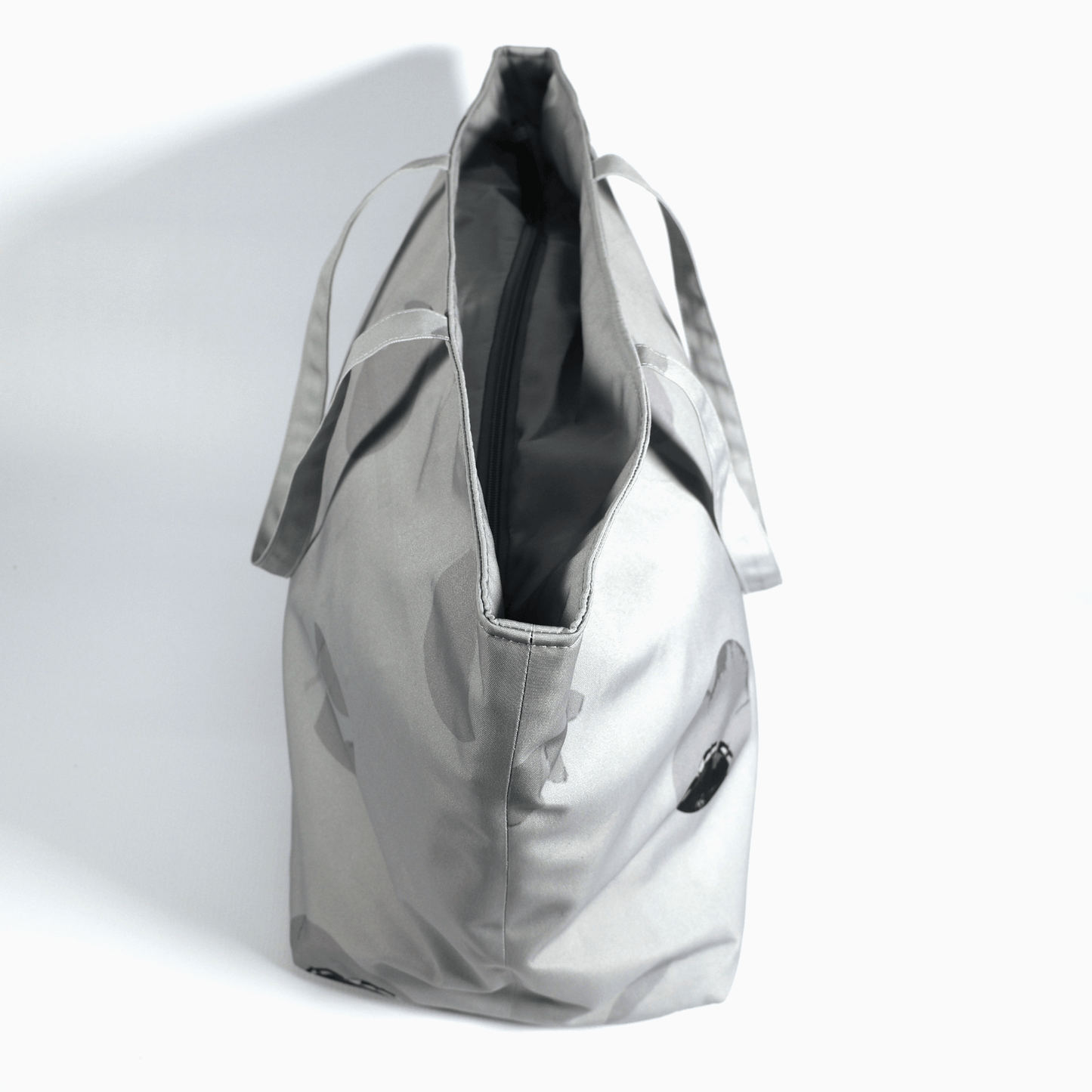 A silver grey carryall bag with abstract floral design. Side view.