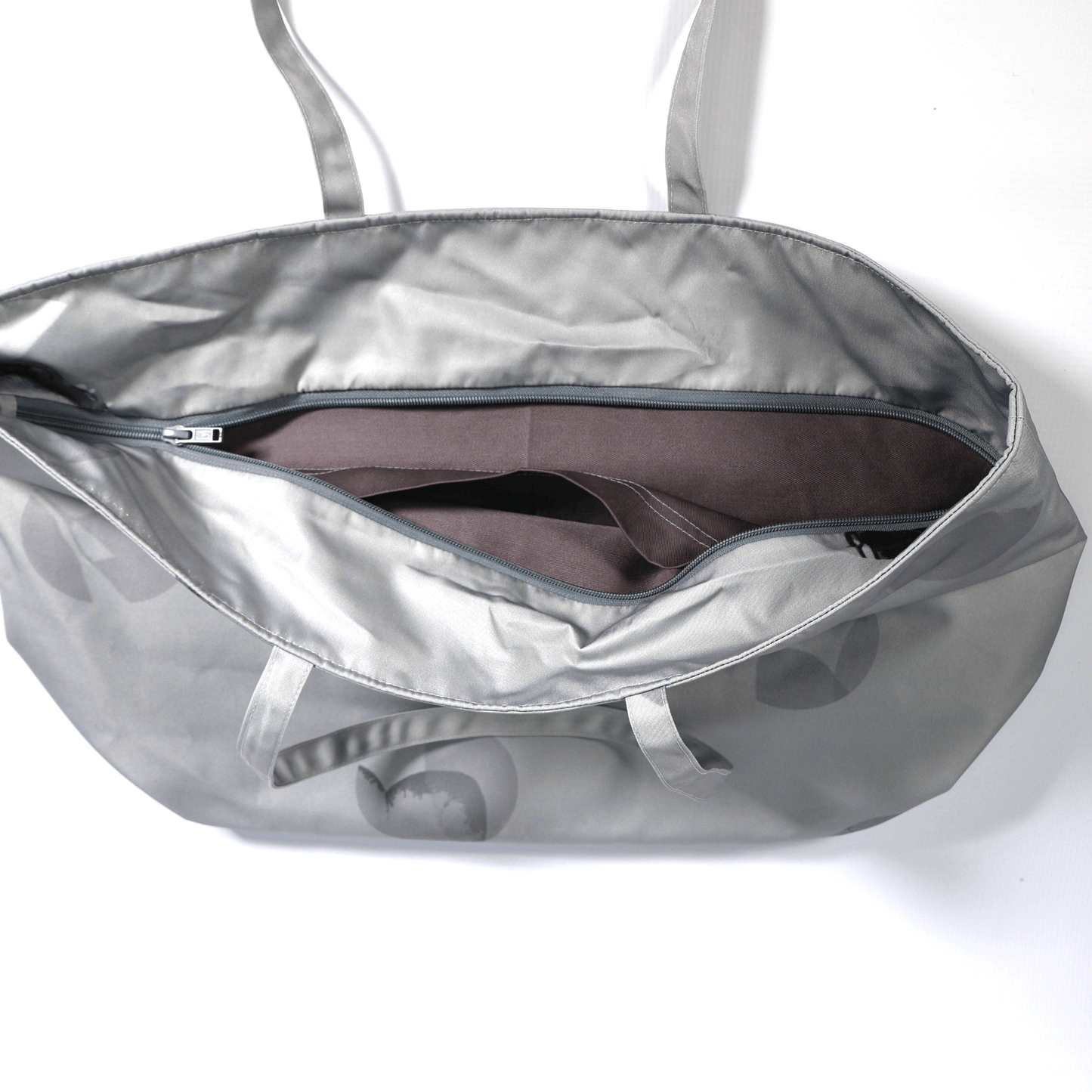 A silver grey carryall bag with abstract floral design. Top view. Open zipper.