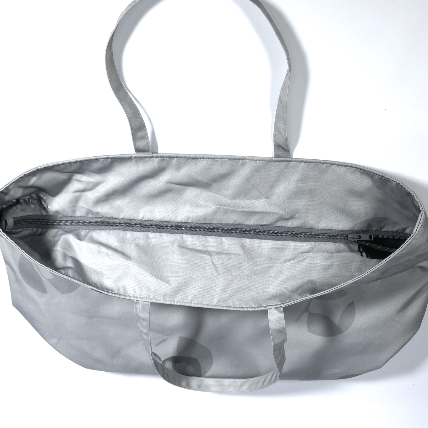 A silver grey carryall bag with abstract floral design. Top view.