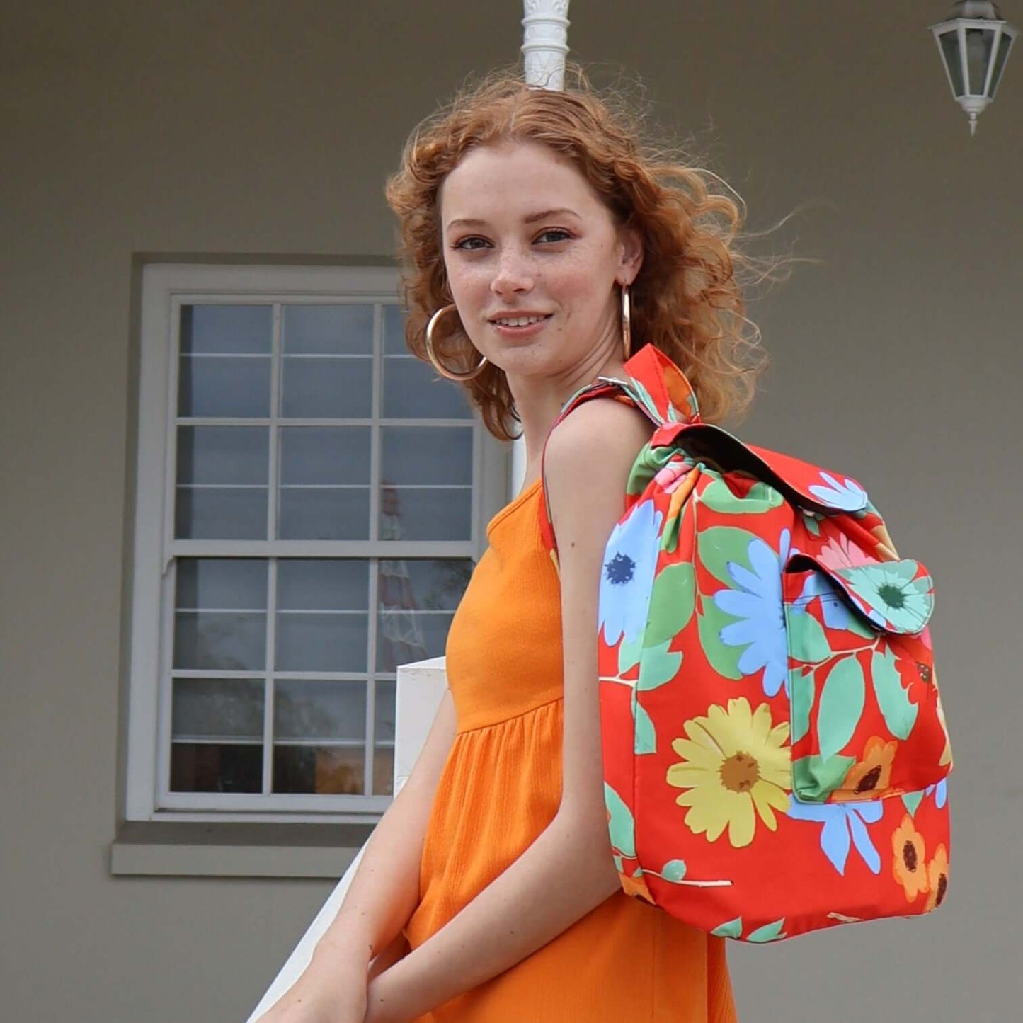 Model with bright red, floral daisy backpack.