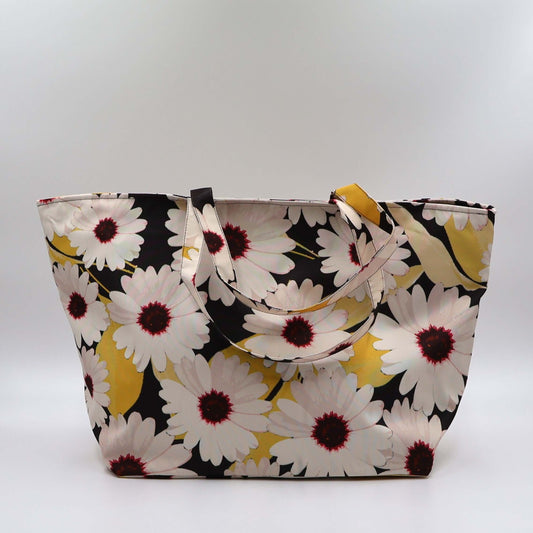 A black carryall bag with big white daisy floral design.