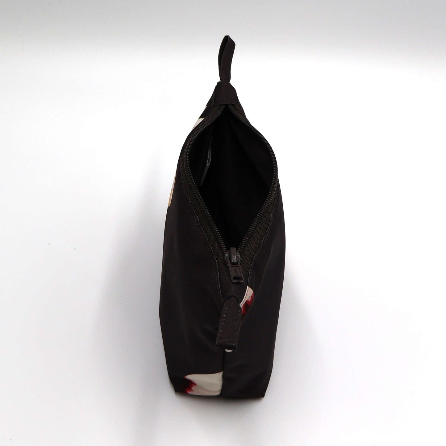 Dark brown/black makeup bag with white daisy floral design, perfect for organizing beauty products. Top view. Open.