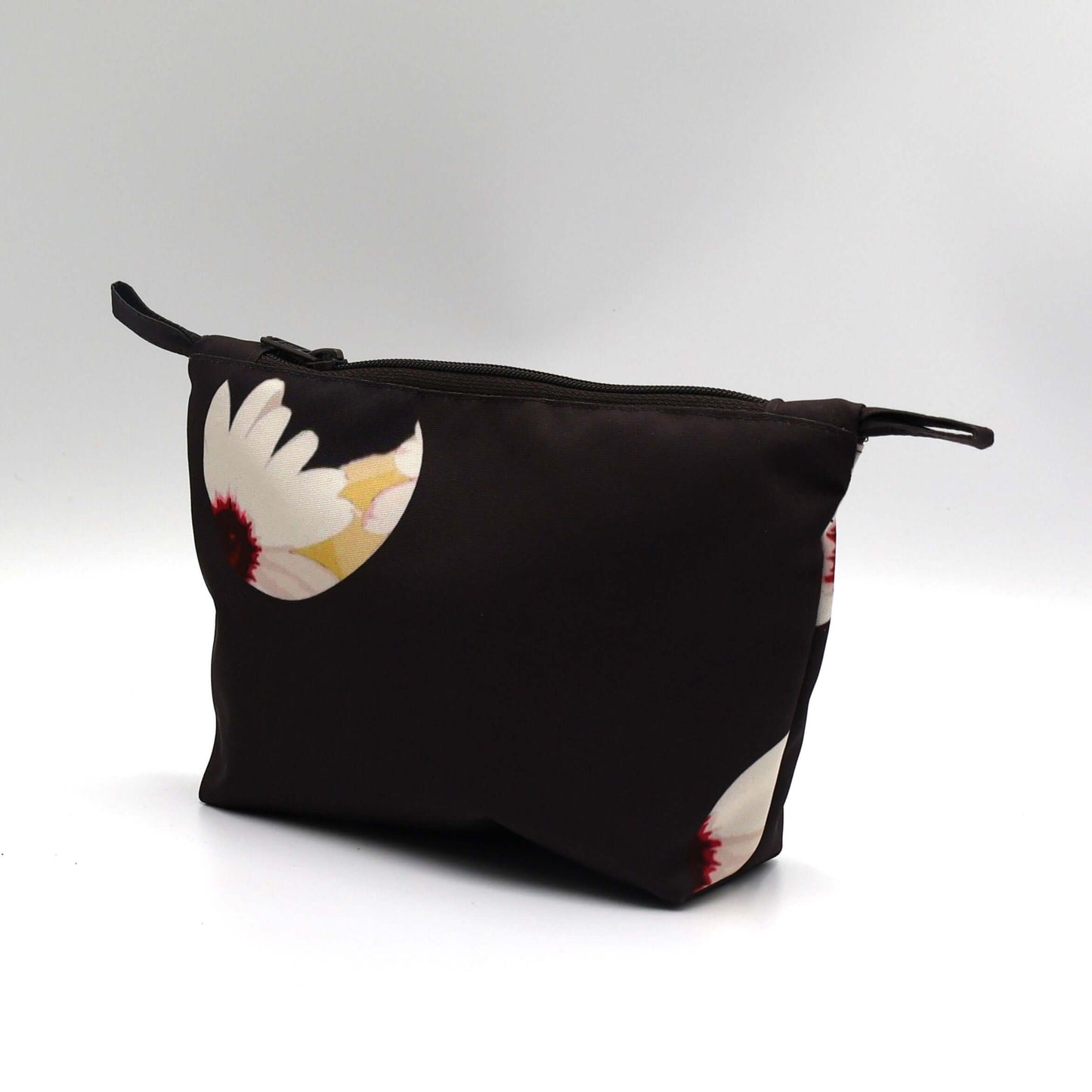Dark brown/black makeup bag with white daisy floral design, perfect for organizing beauty products. Side view.