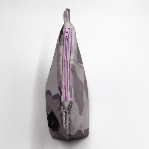Makeup bag in mauve, dark grey and dusky grey floral design. Closed zipper. Top view.