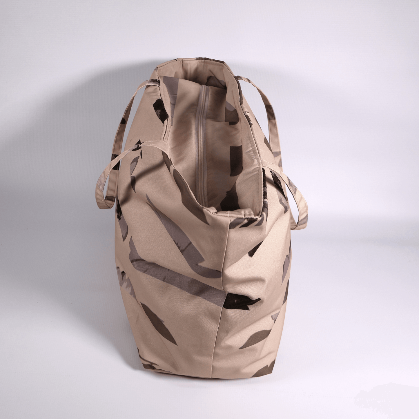 A dusky light peach carryall bag with a stripe design. Side view.