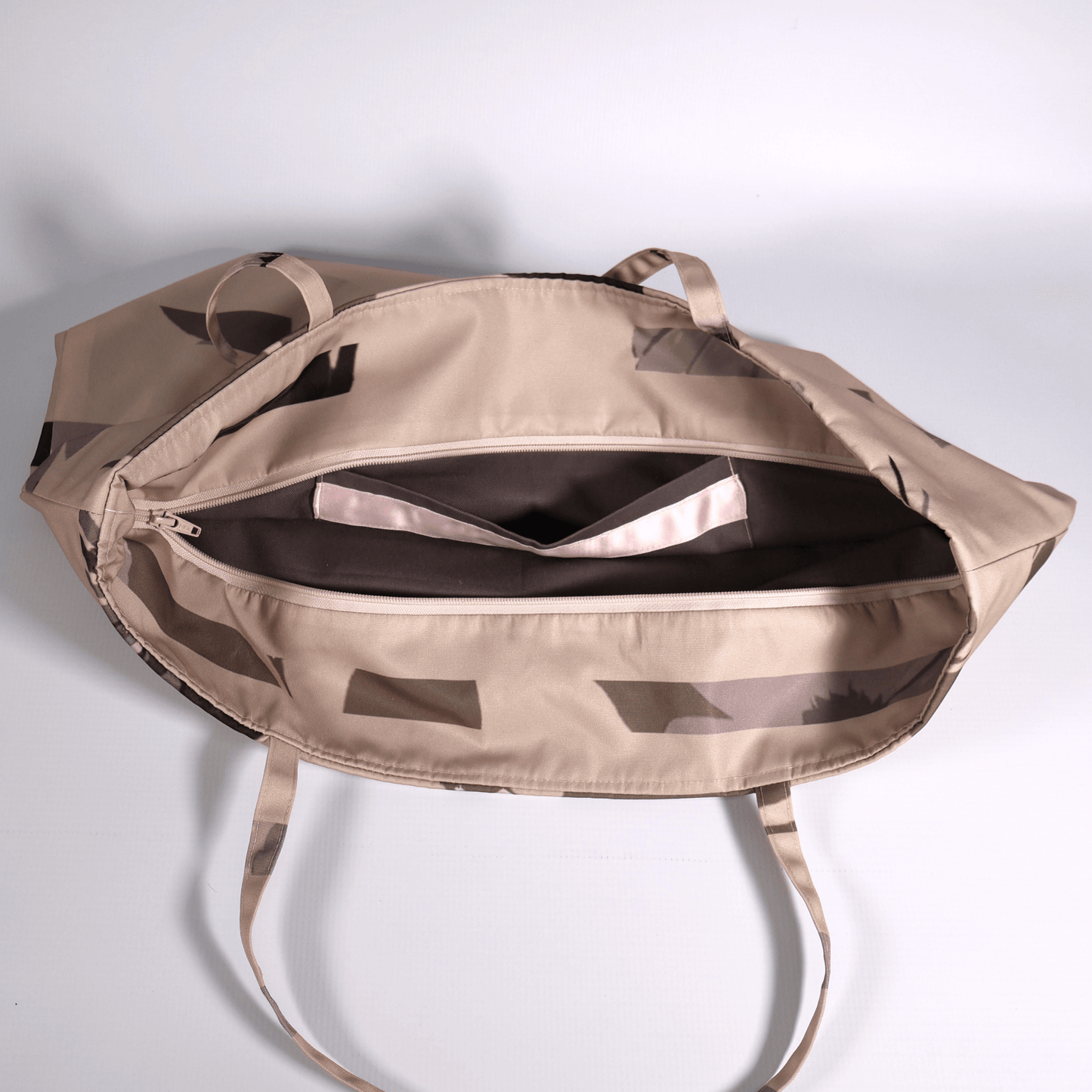 A dusky light peach carryall bag with a stripe design. Top view. Zipper open.