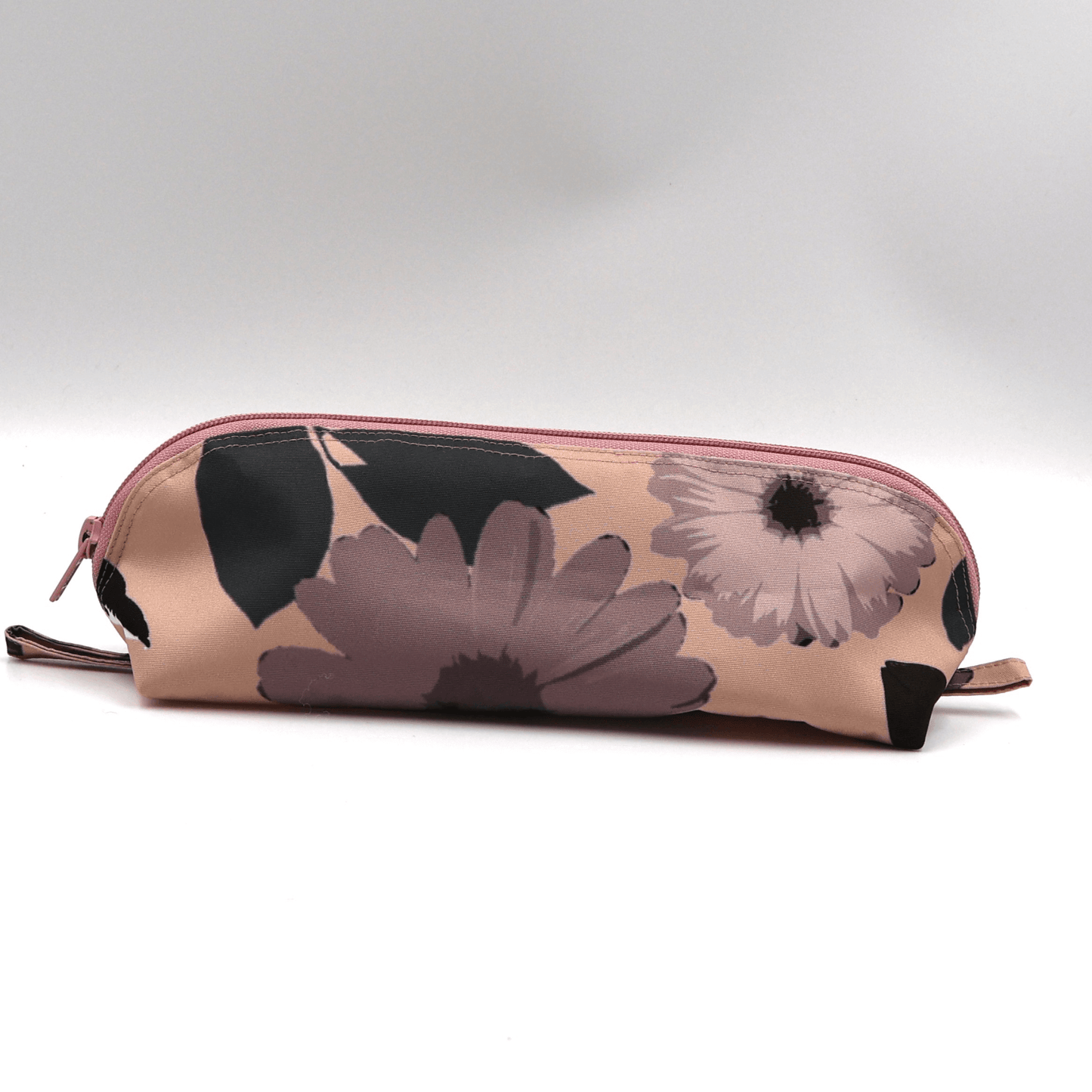 Pencil bag in dusky pink and dark grey daisy floral design on soft peach background.