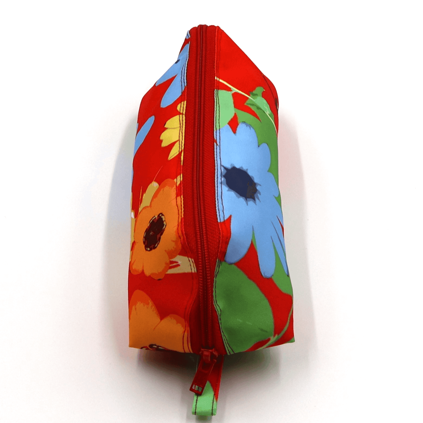 Pencil bag in bright colourful daisy floral design on red background. Top view closed.