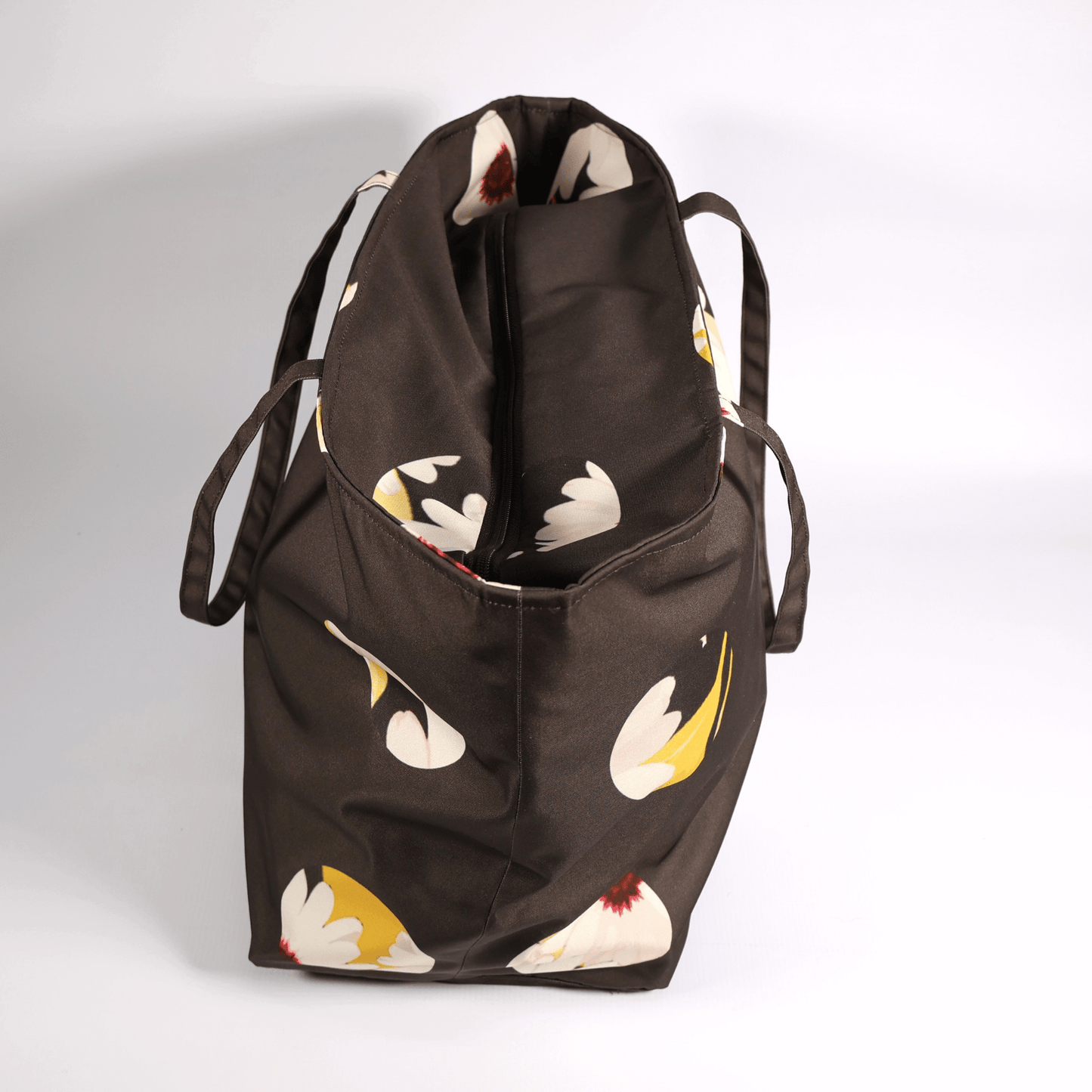 A dark grey/black carryall bag with a white abstract floral design. Top view. Closed.