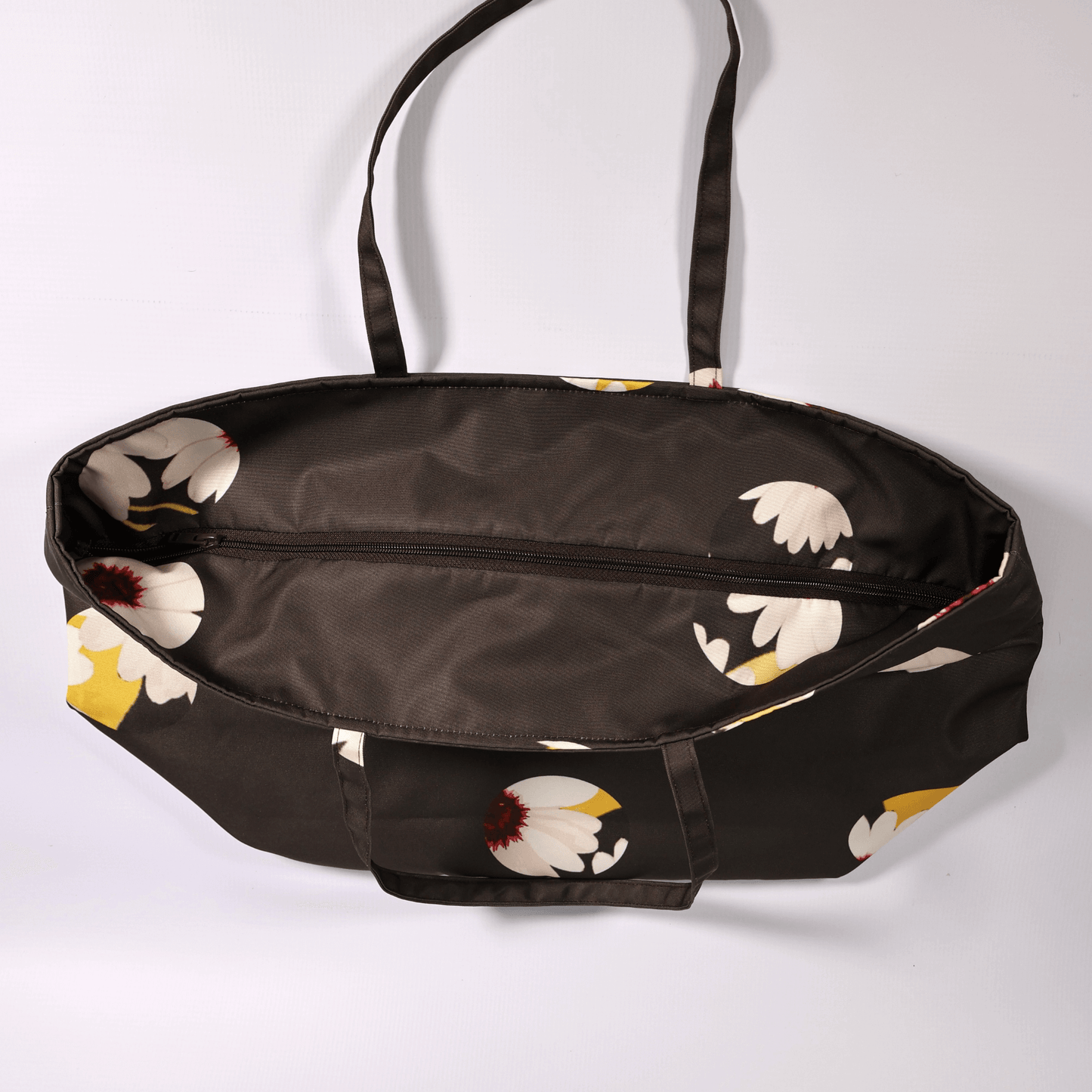 A dark grey/black carryall bag with a white abstract floral design. Top view.