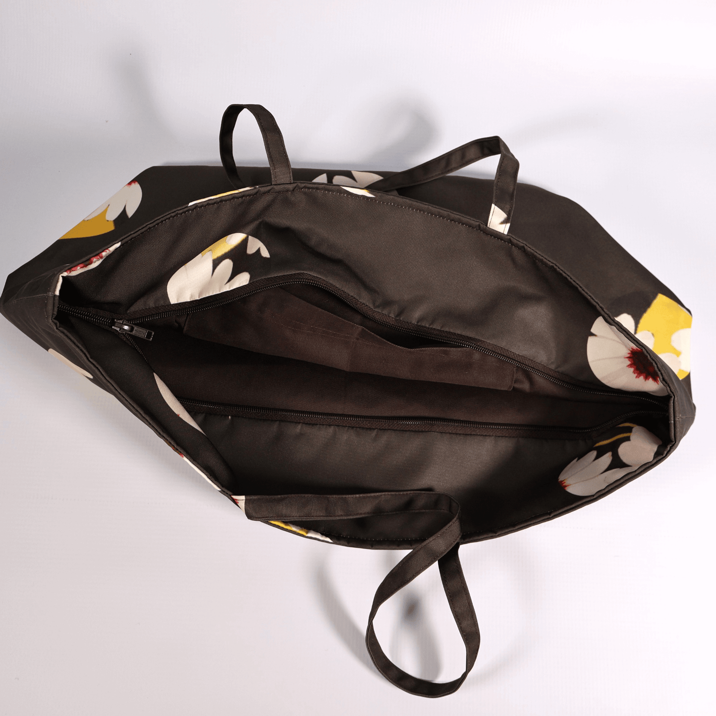 A dark grey/black carryall bag with a white abstract floral design. Open view.