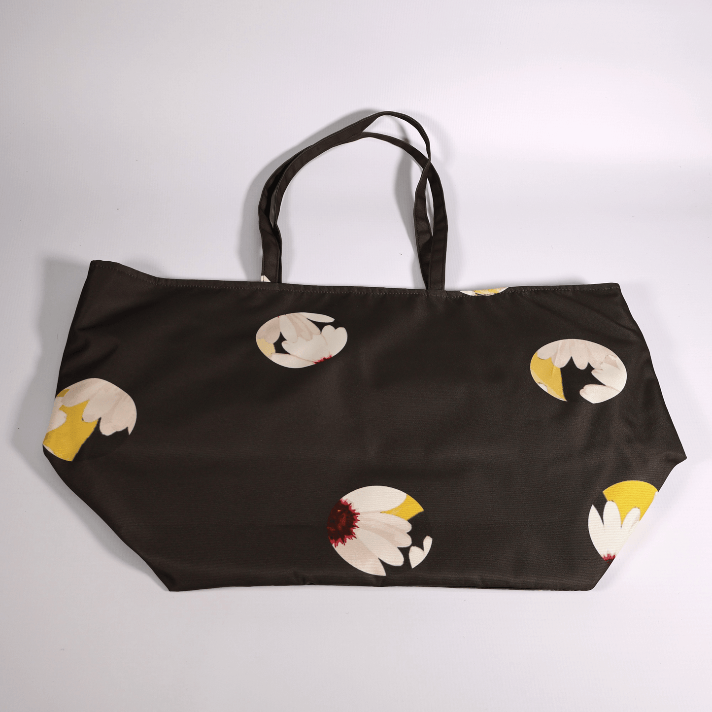 A dark grey/black carryall bag with a white abstract floral design. Flat view.