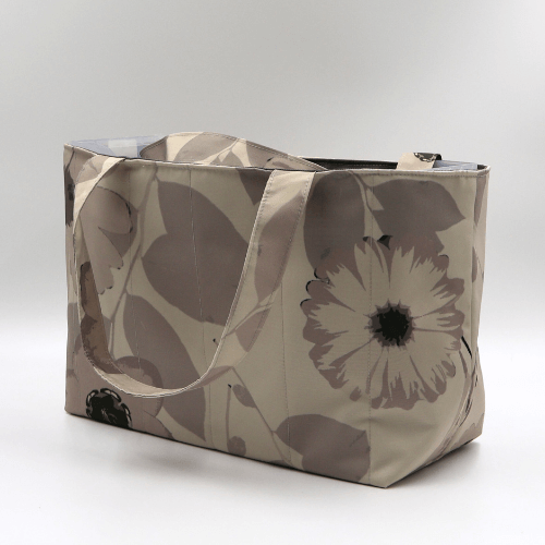 Medium teacher/book bag with floral daisy design in dark and light beige and taupe. Side angle.
