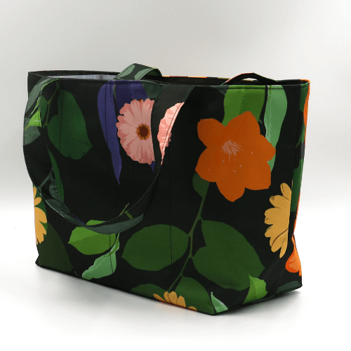 Medium teacher/book bag with bright, daisy design on a black background. Carry books and crafts. Side view.