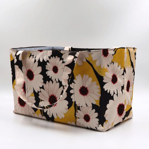 Large teacher/book bag with white, daisy design on a black background. Side view.