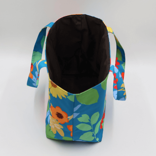 Teacher/book bag with bright floral daisy design on a blue background. Carry books and crafts. Top view without inner.