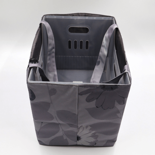 Large teacher/book bag with floral daisy design in dark and light grey on a soft silver-grey background. Top view with plastic inner.